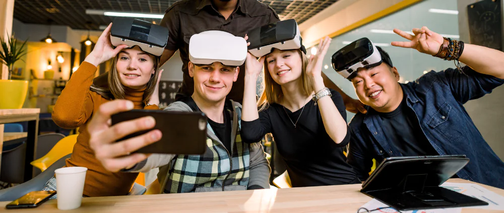 Junge Menschen posieren vor einem Handy mit VR-Brillen auf dem Kopf